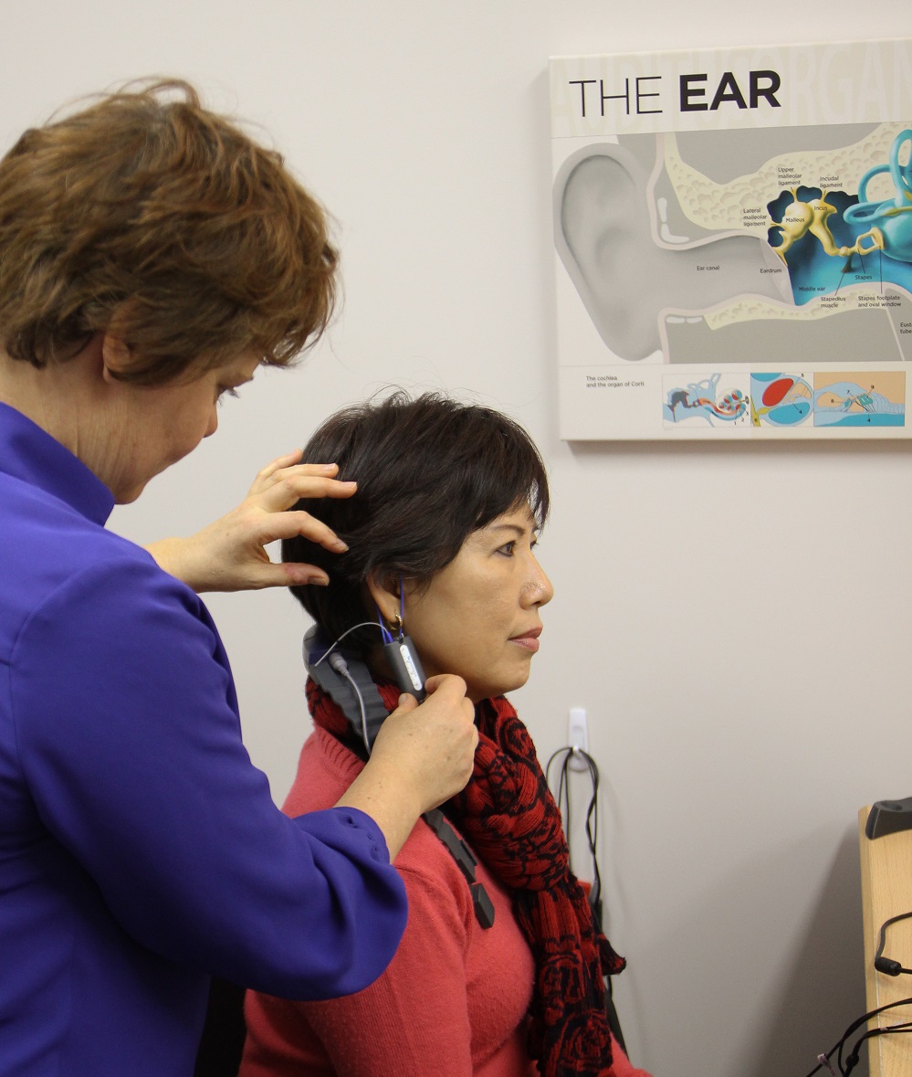 Audiologist fitting hearing aids